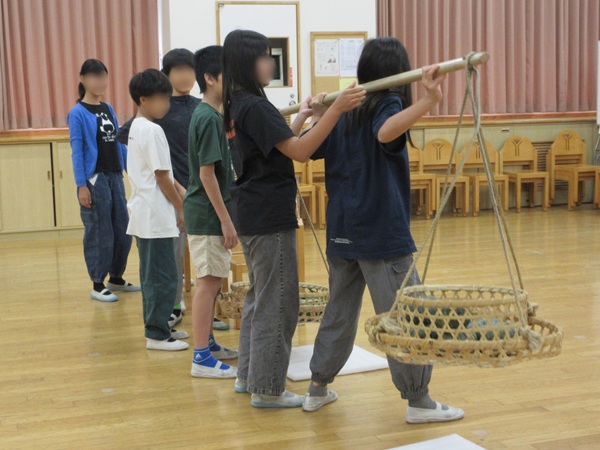 児童たちが「棒手振り」を肩に乗せている写真