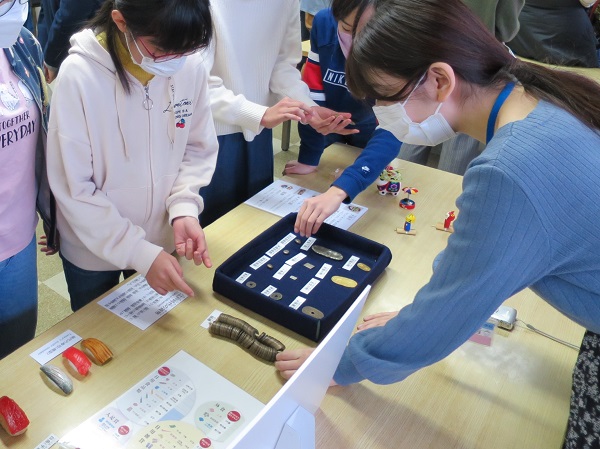 江戸時代の貨幣を説明する学芸員と見ている女の子