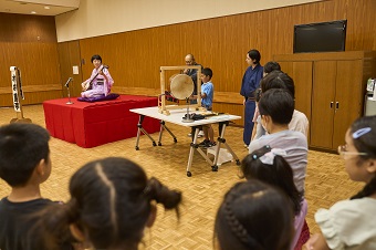 ワークショップでお囃子にあわせて太鼓をたたくこども