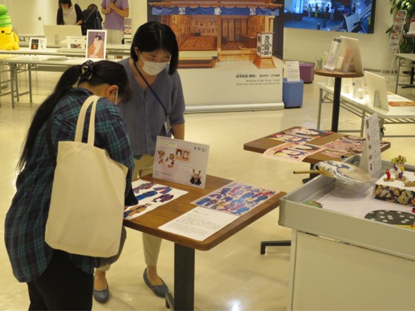 江戸のおもちゃのワークショップに参加する参加者と説明する学芸員